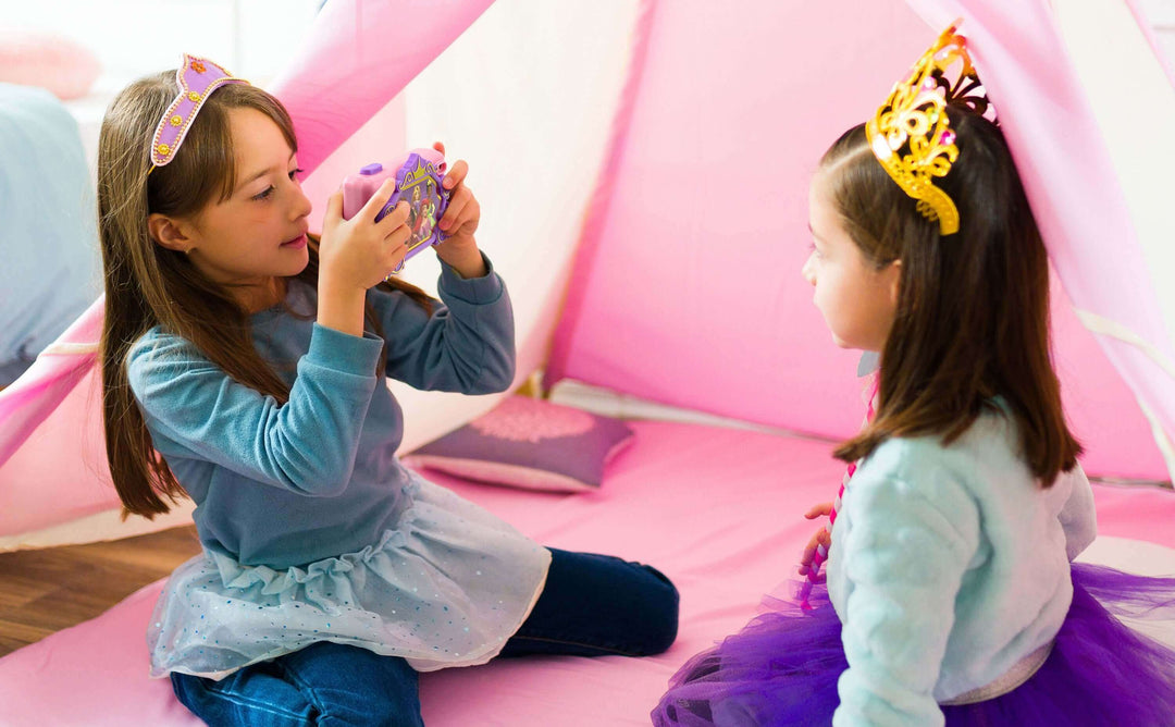 Girls playing with Disney Princess digital camera inside a pink tent