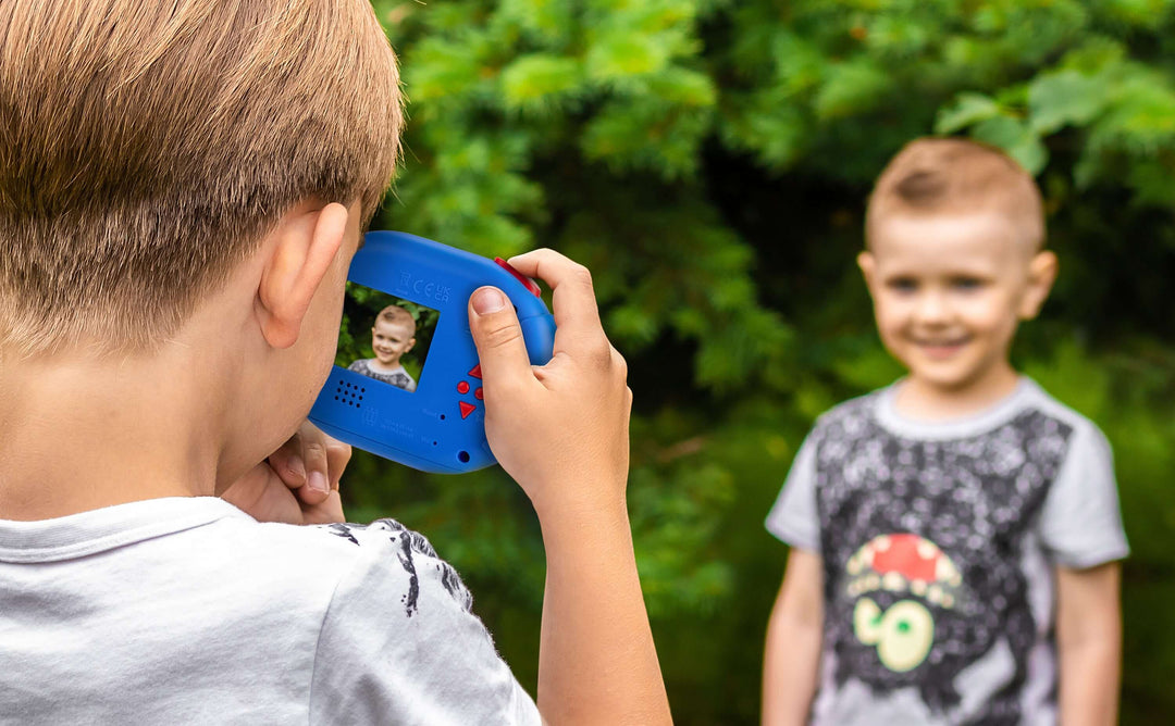 Child using Paw Patrol digital camera to take a photo of another child outdoors