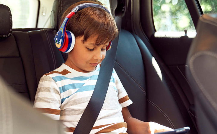 Boy wearing Sonic The Hedgehog Bluetooth headphones in car, enjoying wireless music on a mobile device while seated safely.